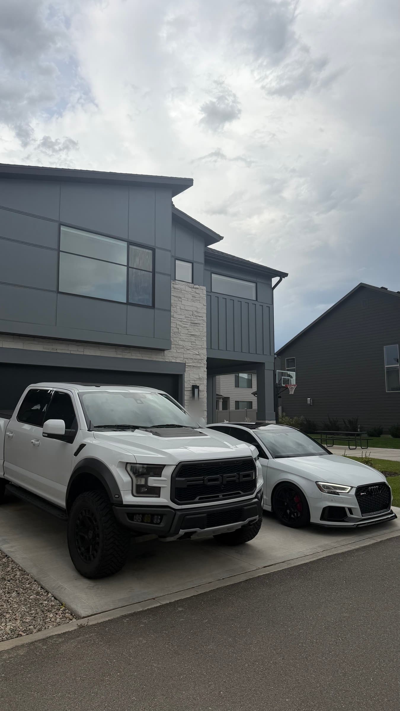A white pickup truck and a white Audi parked in a driveway